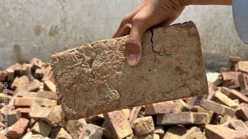 Konstfotografi Hand holding a single stone brick over a pile of rubble