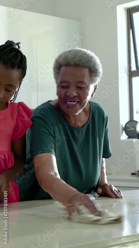 Vertical video: Spraying grandchild in pink dress, gran wiping island, cleaning with sprays and rag