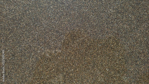 Dark volcanic sand texture background with fine brown and black mineral grains for design.