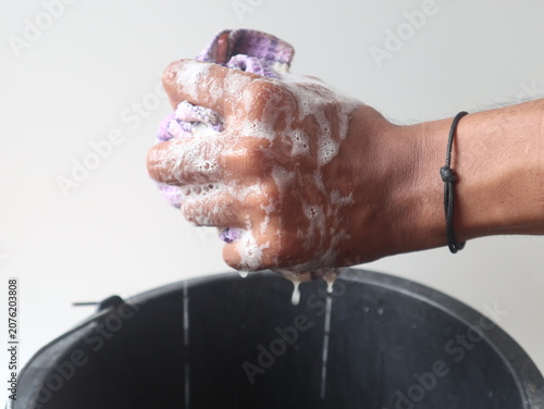 Fotografie Hand wringing soapy cloth over bucket