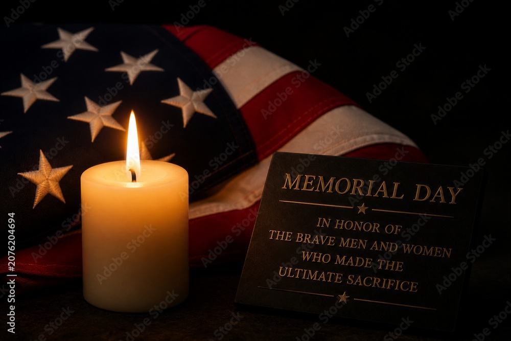 Fototapeta premium Candle glows softly beside an American flag. Black plaque honors brave men and women. Symbolic tribute to those who sacrificed everything. Suitable for solemn remembrance or patriotic events