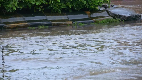cars rush through rain puddle and splash countless transparent water droplets outward on wet urban roadside