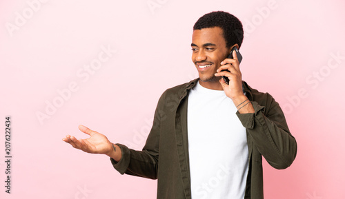 African American man on copyspace pink background keeping a conversation with the mobile phone with someone