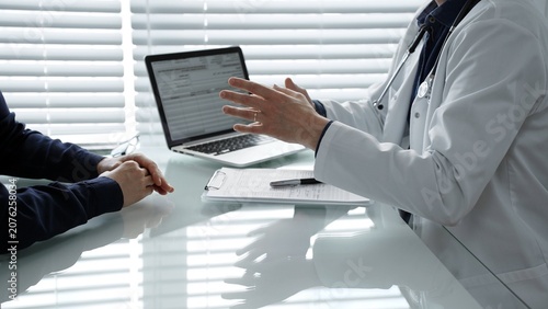 Medical professional using laptop showing patient digital health records, consulting about diagnosis, discussing healthcare during a check up in a modern clinic