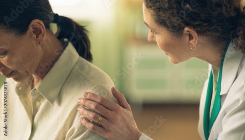A healthcare professional comforts a distressed woman by gently placing a hand on her shoulder in a supportive and compassionate gesture.