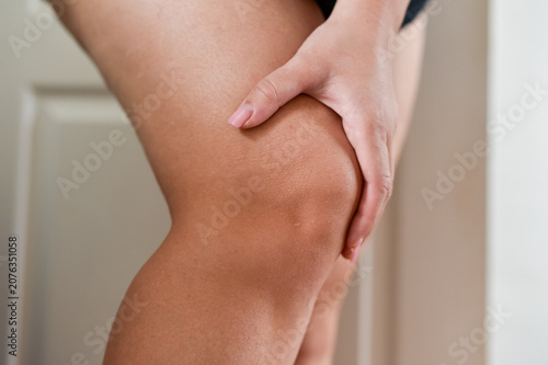 Obraz na plátne Close up of a female leg with a hand holding the thigh above the knee joint