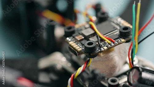 Technician soldering components onto circuit board of disassembled fpv drone