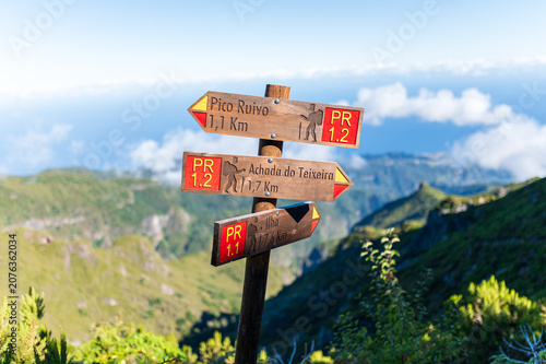 Wooden trail signpost pointing to Pico Ruivo and Achada do Teixeira in the mountains of Madeira island