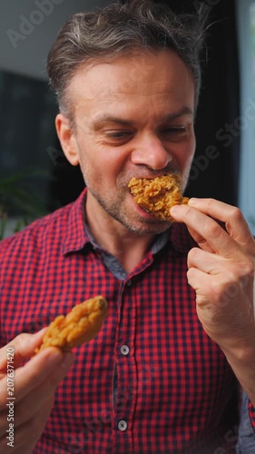 Junk food advertisement concept. Man eating fried chicken, enjoying fast food.
