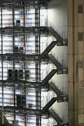 モダンな建物の外壁に連なる非常階段と設備機器が描く幾何学模様