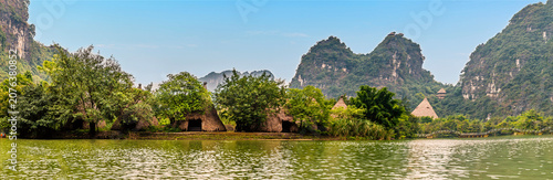 Schilderij op canvas A panorama view of rustic huts with conical thatched roofs nestled among lush gr