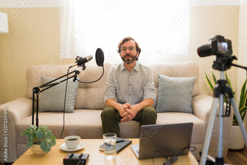 Man creating new content for his channel, sitting on sofa with recording studio equipment for a video podcast