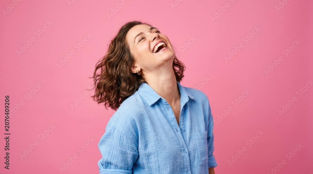 Obraz premium Woman laughing with head tilted back against pink background