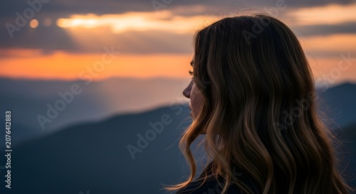 Woman watching sunset over mountain landscape