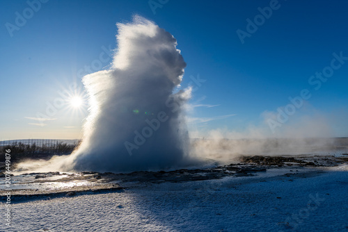 Strokkur geyser eruption with water splash and steam under a bright winter sun, Golden Circle, Iceland