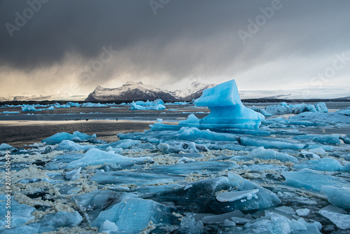 Fotografía Beautiful blue icebergs floating in Jokulsarlon glacier lagoon under a dramatic