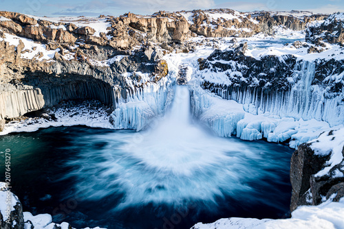 Scenic view of Aldeyjarfoss waterfall in winter with basalt columns in North Iceland.