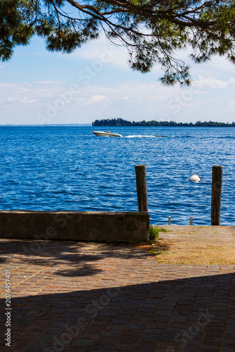 Obraz na plátně Runabout boat speeding across the waters of Lake Garda