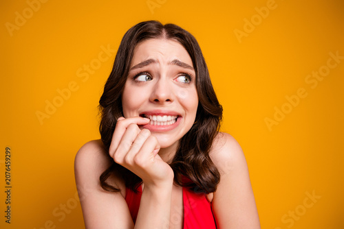 Canvastavla Nervous woman biting her nails in an anxious portrait, worried young adult glanc