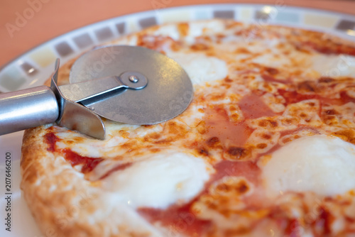 Cheese Pizza with Pizza Cutter served on a plate
