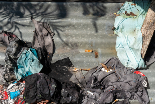 Billede på lærred Piles of clothing and trash left on corrugated metal sheets