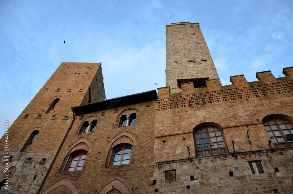 Obraz premium San Gimignano, Italy 03.04.2020: Town Hall (also known as the Palazzo del Popolo or Palazzo Nuovo del Podestà) and the Torre Grossa in San Gimignano