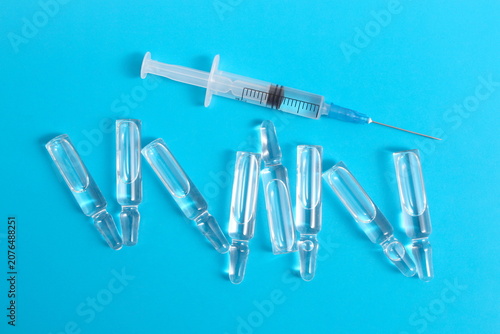 Obraz na plátně On a blue background are glass ampoules with medicine and a syringe