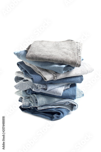 On a white background, many pairs of jeans are folded into a stack.