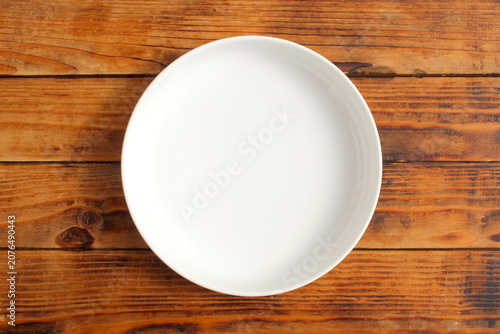 Foto There is an empty ceramic plate on a wooden background.