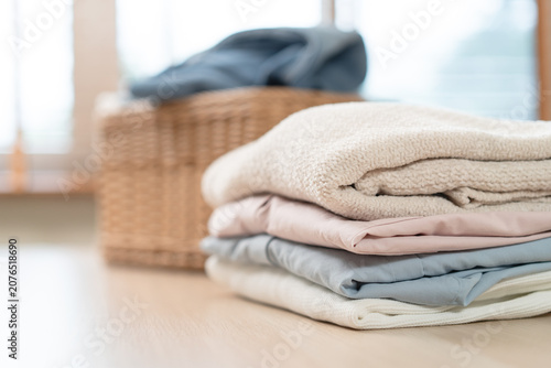 Foto A neat stack of clean folded clothes on wooden table with wicker laundry basket