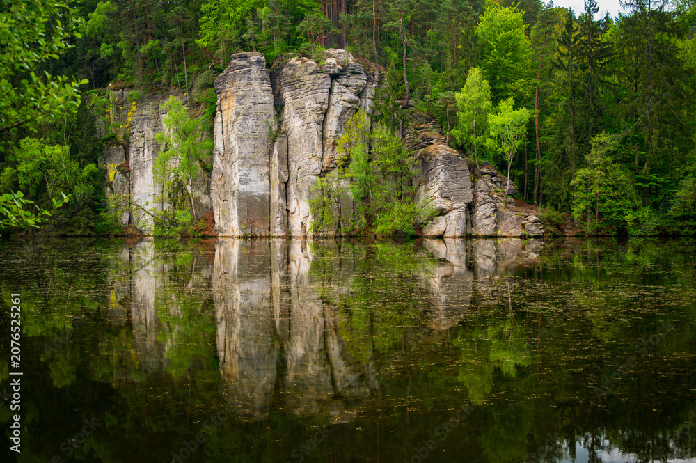 Fototapeta premium Iconic sandstone cliffs reflected in the calm waters of Vezicky Pond (Vezicky rybnik in czech) in the beautiful Bohemian Paradise, Czech Republic, a famous scenic destination popular with tourists.