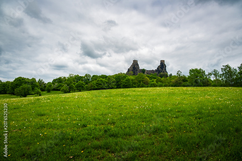 Panoramic view of the iconic Trosky Castle Ruins rising above forests and meadows in the beautiful Bohemian Paradise, Czech Republic, beneath dramatic summer skies.