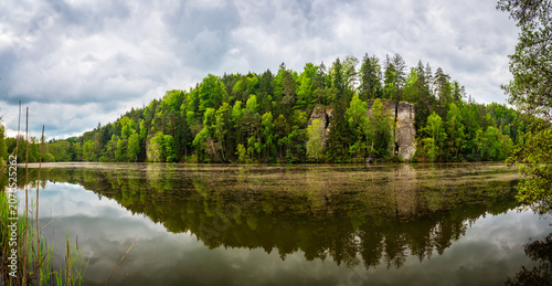 Iconic sandstone cliffs reflected in the calm waters of Vezicky Pond (Vezicky rybnik in czech) in the beautiful Bohemian Paradise, Czech Republic, a famous scenic destination popular with tourists.
