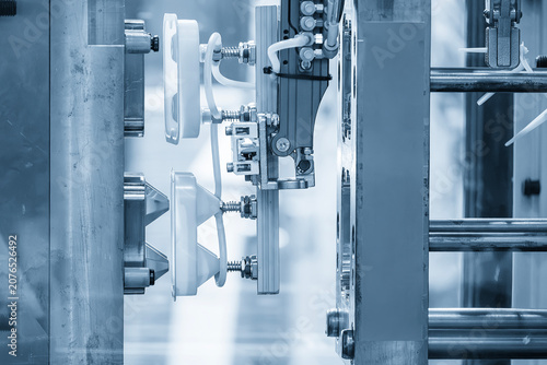 Industrial robotic arm gripping and removing plastic parts from an injection molding machine.