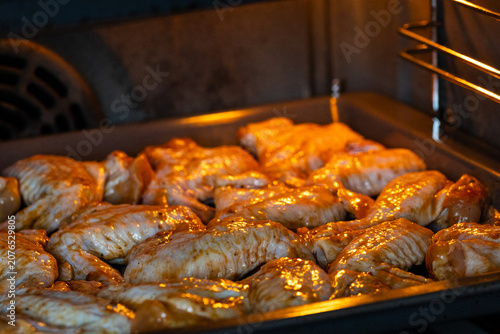 Obraz na plátně Raw chicken wings marinated in a golden sauce placed in a baking tray inside an