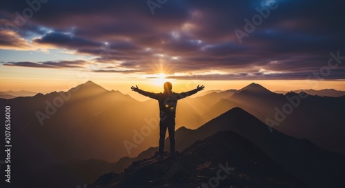 A person embracing the world with arms wide at a breathtaking mountain sunset