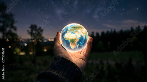 Hands holding glowing earth globe at night