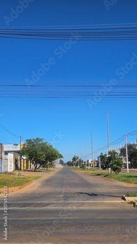 Perspective view of a deserted residential road with power lines stretching into the distance