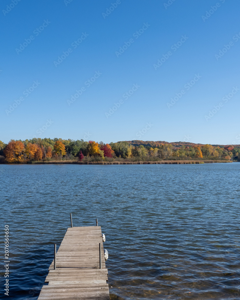 Fototapeta premium Wooden dock overlooking lake with fall foliage