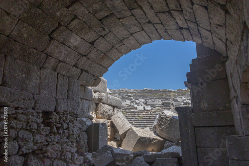 An ancient city located high in the mountains. The vaults of the buildings in the ancient city are made of huge stone blocks. Stone arches of ancient buildings leading to the amphitheater.