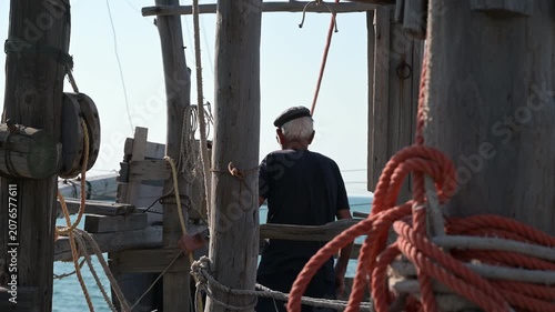 pescatori al lavoro su di un antico trabucco in legno sulle coste del gargano in puglia