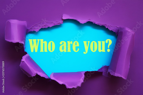 Who Are You Question Revealed Through Torn Magenta Paper On Purple Background For Identity Self Discovery And Personal Growth Concept