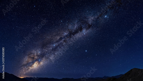 The Milky Way galaxy stretches across the night sky above a mountain range at dusk