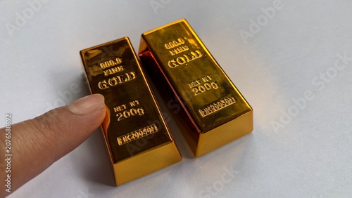 Fotografie Two gold bars placed side by side with finger pointing, highlighting engraved “f