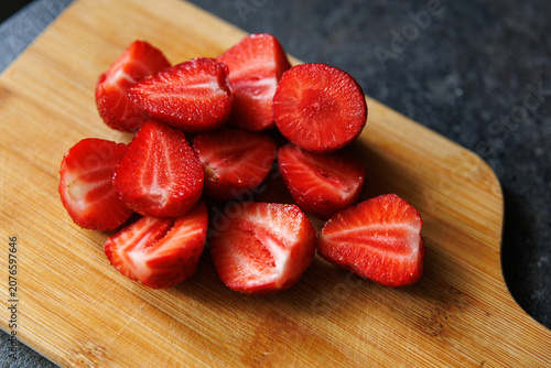 фотографія Strawberry sliced pieces on wooden cutting board in kitchen, fresh juicy red ber