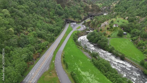 Aerial drone flyover of road tunnel and mountain valley covered in trees, Norway