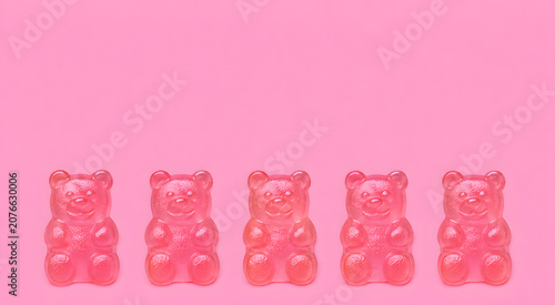 Five pink gummy bears in a row on pink background