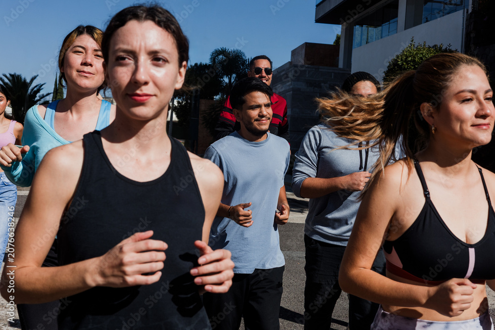 Obraz premium Group of latin people running and training together in mexican street in Mexico Latin America, hispanic runners club preparing a race