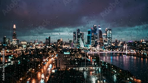 Rainy night cityscape with glowing lights and reflections on wet window pane