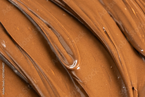 Macro texture of glossy chocolate nut cream swirling patterns